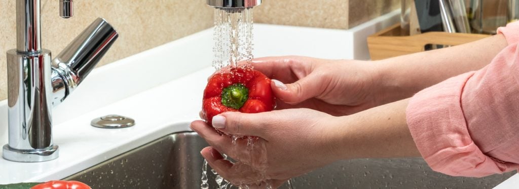 Woman washing a sweet pepper close-up under running water