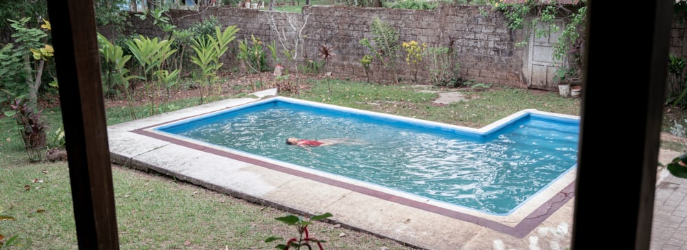 A woman swimming in a pool in a back yard