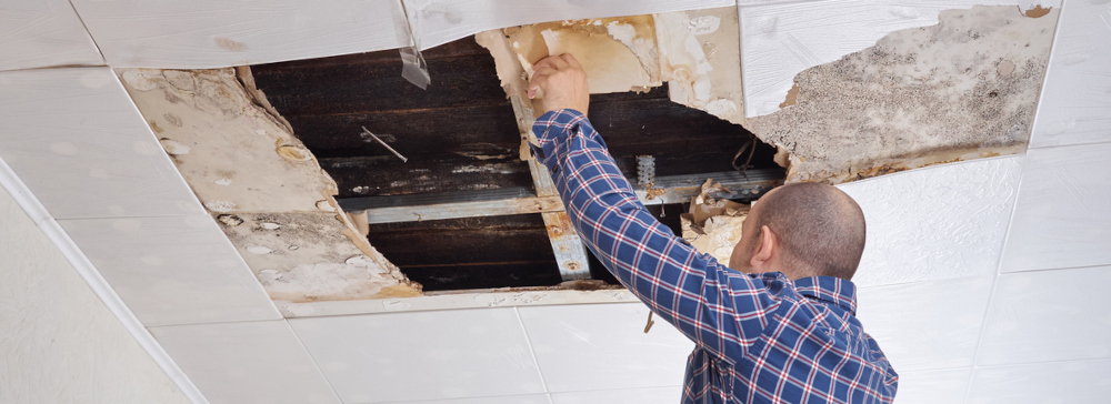 A man repairing damaged ceiling panels