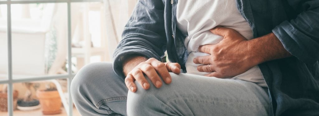 Man suffering with severe stomach pain sitting at home