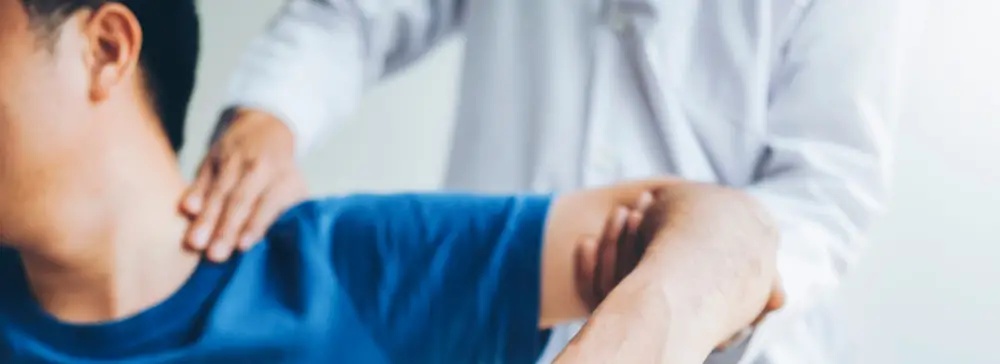 Doctor examining a patient's injured shoulder and arm