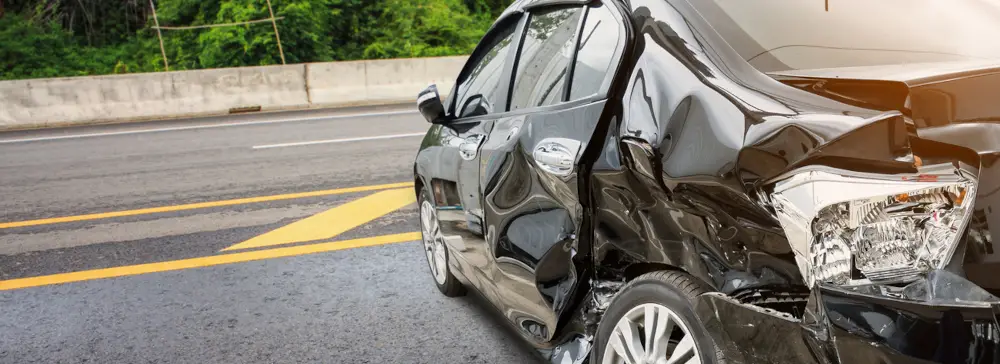 A black car with extensive damage from a side impact accident