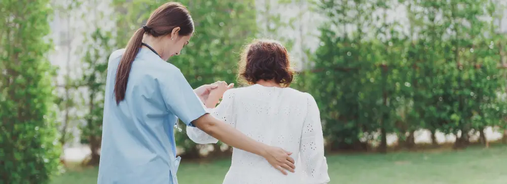 A female nurse guiding an elderly resident in the garden at a nursing home