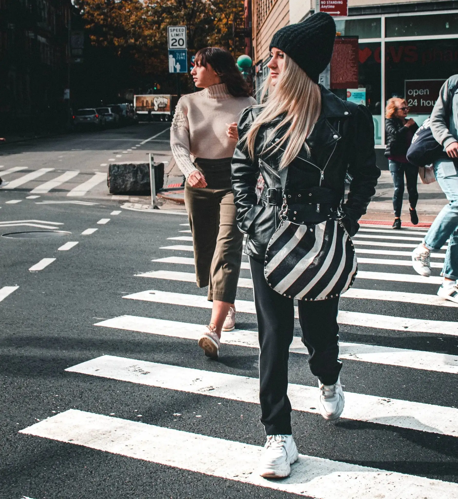 Two pedestrians crossing a crosswalk in the city