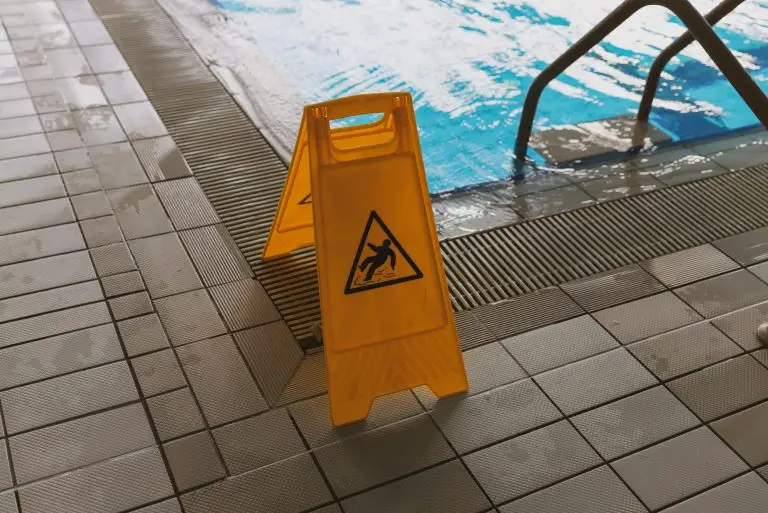 Yellow wet floor warning sign beside an indoor swimming pool, representing a slip and fall accident and potential compensation claim in Florida.